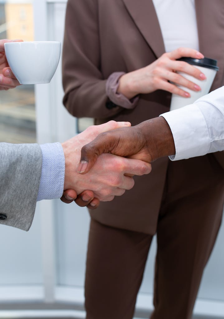 Business professionals handshake demonstrating diversity and collaboration in an office setting.